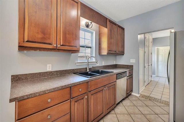 kitchen featuring a sink, stainless steel appliances, dark countertops, and light tile patterned floors