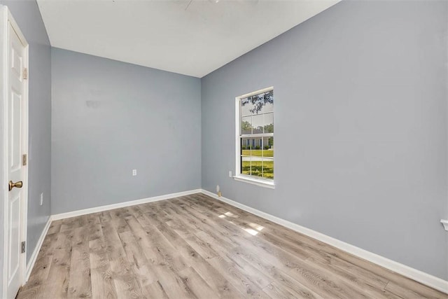 spare room with baseboards and light wood-style flooring