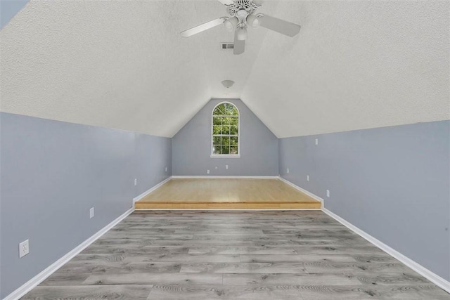 additional living space featuring lofted ceiling, ceiling fan, a textured ceiling, and wood finished floors
