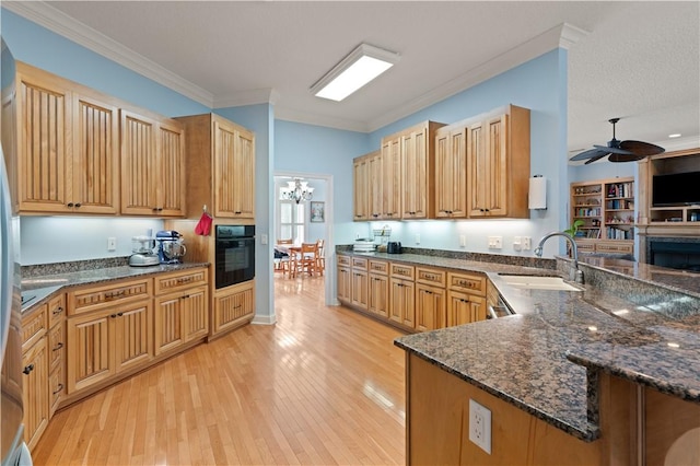 kitchen with a sink, oven, a peninsula, light wood finished floors, and ceiling fan