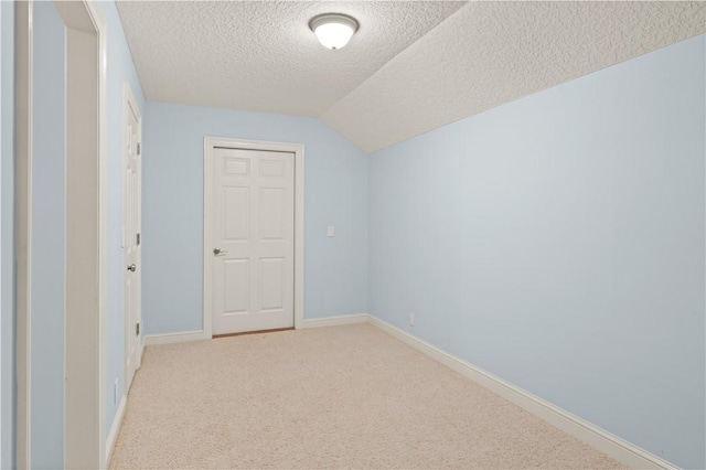 bonus room featuring a textured ceiling, light colored carpet, baseboards, and lofted ceiling
