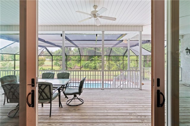 wooden deck featuring a lanai, a ceiling fan, an outdoor pool, and outdoor dining area