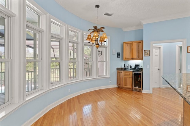 kitchen featuring wine cooler, a chandelier, light wood-type flooring, healthy amount of natural light, and a textured ceiling