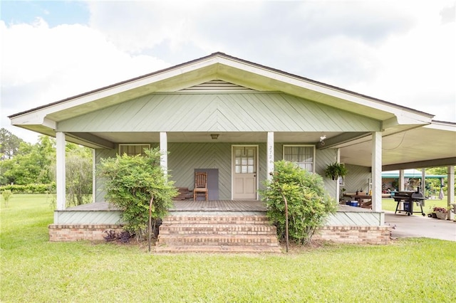 rear view of house featuring a lawn and a porch