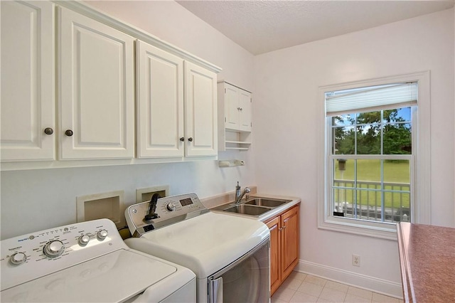 laundry room with cabinets, washing machine and dryer, light tile patterned floors, and sink