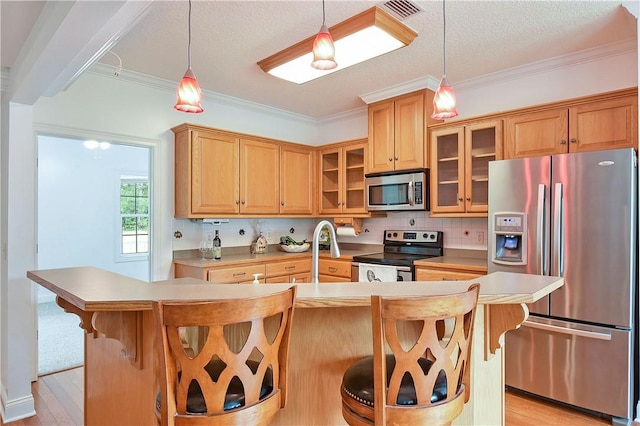 kitchen featuring a kitchen breakfast bar, a center island with sink, light hardwood / wood-style flooring, and appliances with stainless steel finishes