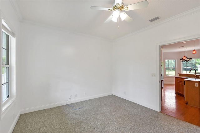 empty room featuring hardwood / wood-style floors, ceiling fan with notable chandelier, crown molding, and sink