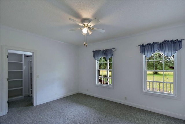 unfurnished bedroom featuring carpet flooring, ceiling fan, a spacious closet, and a textured ceiling