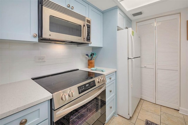 kitchen with light stone countertops, light tile patterned floors, stainless steel appliances, and tasteful backsplash