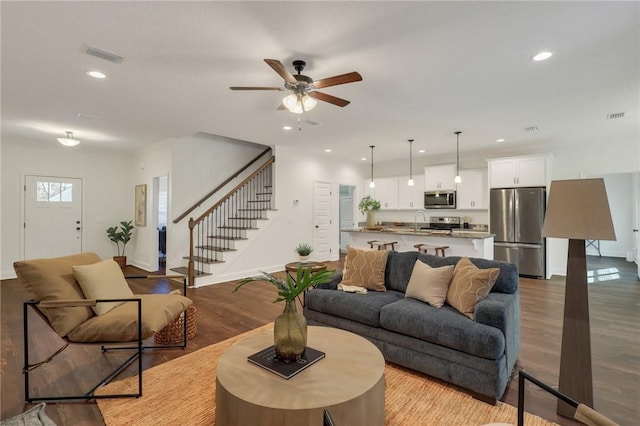 living room featuring ceiling fan, sink, and light hardwood / wood-style floors