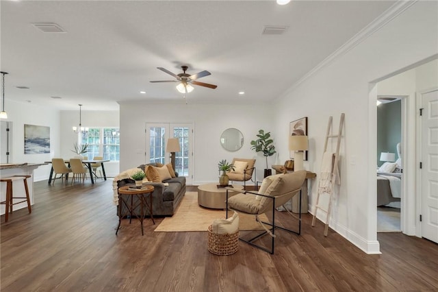 living room featuring crown molding, dark hardwood / wood-style floors, ceiling fan with notable chandelier, and french doors