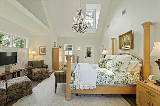 219 Abbott Ln, Saint Simons Island, GA 31522 - bedroom with high vaulted ceiling, a chandelier, multiple windows, and wood finished floors