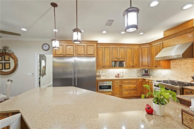219 Abbott Ln, Saint Simons Island, GA 31522 - kitchen with high quality appliances, wall chimney exhaust hood, brown cabinets, light stone counters, and crown molding