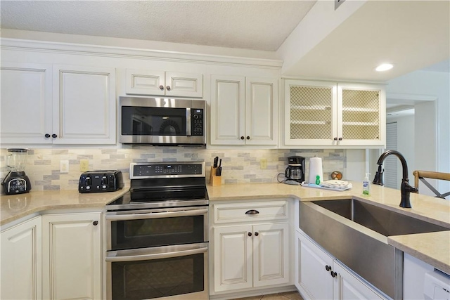 kitchen featuring white cabinets, decorative backsplash, sink, and appliances with stainless steel finishes