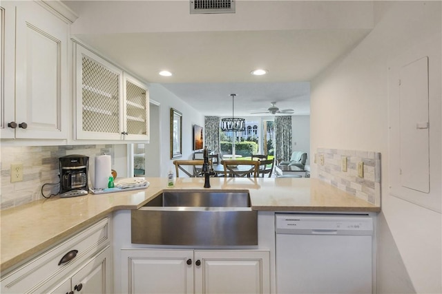 kitchen featuring dishwasher, sink, backsplash, kitchen peninsula, and white cabinets