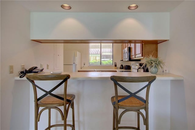 kitchen with a kitchen bar and white appliances