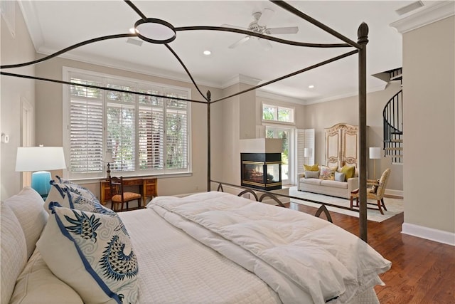 bedroom with a multi sided fireplace, ceiling fan, hardwood / wood-style floors, and ornamental molding