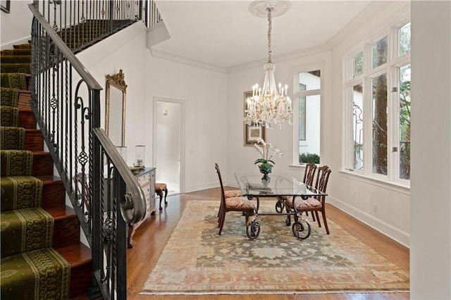 dining area featuring ornamental molding, wood-type flooring, and an inviting chandelier