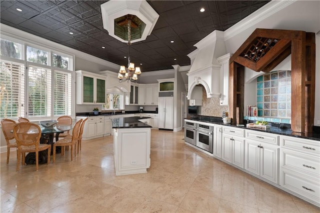 kitchen featuring white cabinets, an inviting chandelier, oven, and crown molding