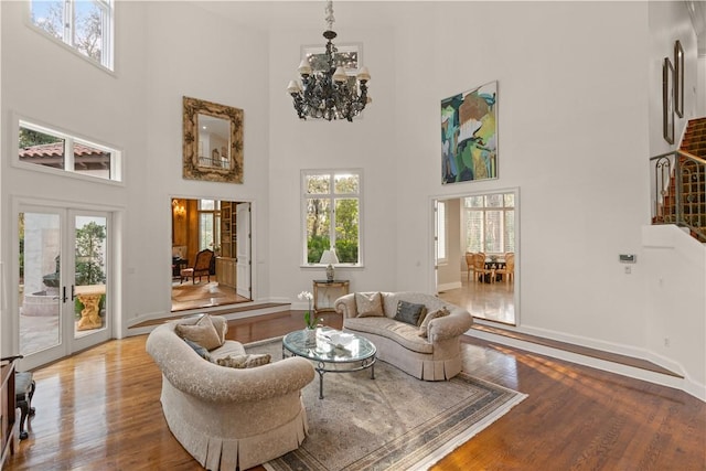 living room with hardwood / wood-style floors, french doors, a chandelier, and a high ceiling