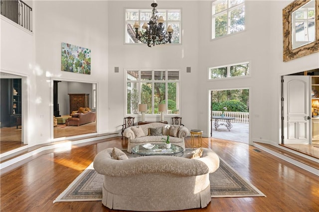 living room with a high ceiling, an inviting chandelier, and wood-type flooring