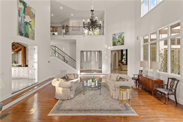 living room featuring crown molding, hardwood / wood-style floors, a chandelier, and a high ceiling