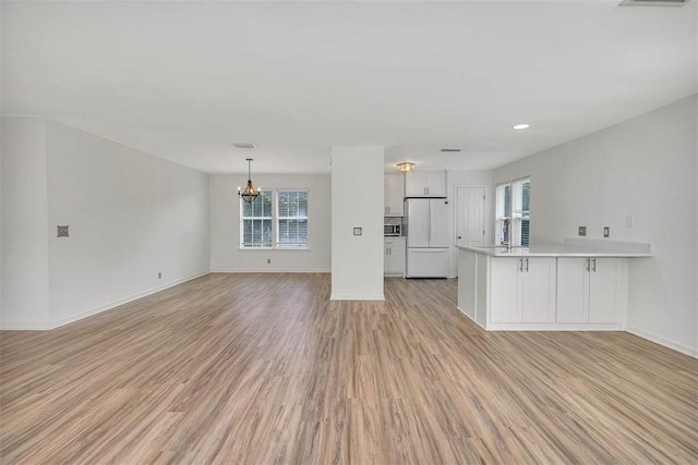 unfurnished living room featuring light hardwood / wood-style flooring, a notable chandelier, and sink