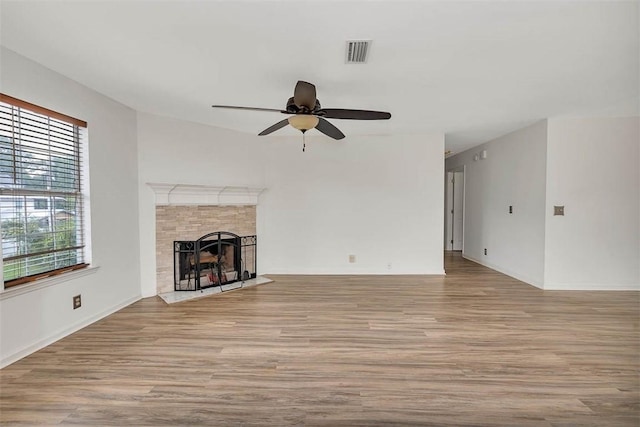 unfurnished living room with a tile fireplace, ceiling fan, and light wood-type flooring