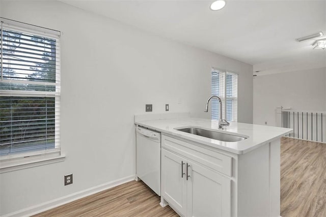 kitchen with dishwasher, sink, kitchen peninsula, white cabinets, and light wood-type flooring