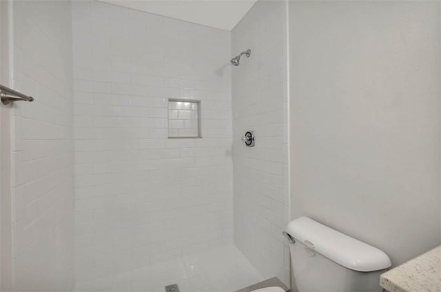 bathroom with a tile shower and toilet