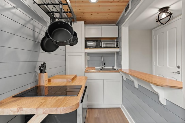 669 N Golf Villas, Saint Simons Island, GA 31522 - kitchen with wooden counters, light wood-style floors, black electric stovetop, white cabinetry, and wooden ceiling