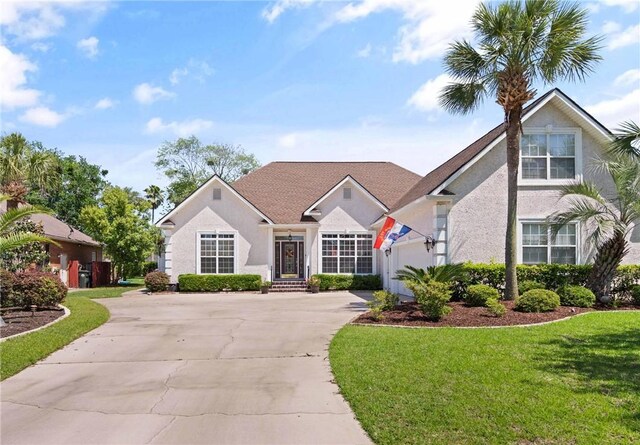 106 Hickory Pne, Brunswick, GA 31523 - view of front of house featuring stucco siding, driveway, a front yard, and a garage