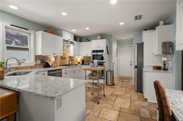 403 Indigo, Saint Simons Island, GA 31522 - kitchen featuring stone tile floors, visible vents, a peninsula, stainless steel appliances, and a sink