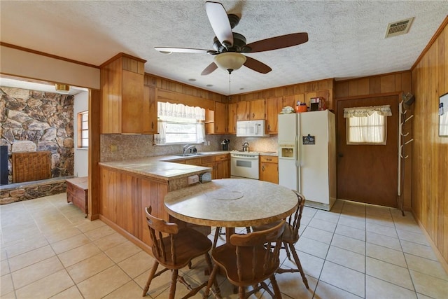 706 Jenkins St, Blackshear, GA 31516 - kitchen with white appliances, light tile patterned floors, brown cabinets, a ceiling fan, and wood walls