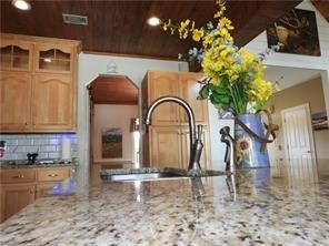 105 Lonnie Johnson Rd, Hazlehurst, GA 31539 - kitchen featuring light stone countertops, decorative backsplash, and glass insert cabinets