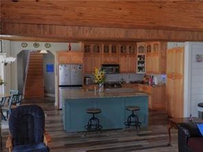 105 Lonnie Johnson Rd, Hazlehurst, GA 31539 - kitchen featuring freestanding refrigerator, a center island, glass insert cabinets, a breakfast bar, and wood finished floors