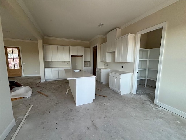 kitchen with crown molding, a breakfast bar, a kitchen island, and white cabinets