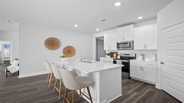 1037 Lakes Blvd, Brunswick, GA 31525 - kitchen with appliances with stainless steel finishes, a center island with sink, dark wood-style flooring, a breakfast bar area, and recessed lighting