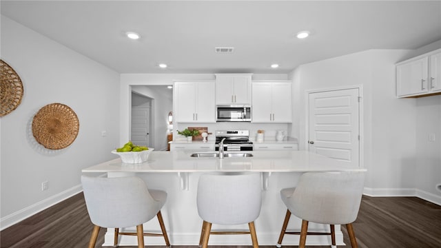 1037 Lakes Blvd, Brunswick, GA 31525 - kitchen with stainless steel appliances, dark wood finished floors, light countertops, white cabinetry, and an island with sink