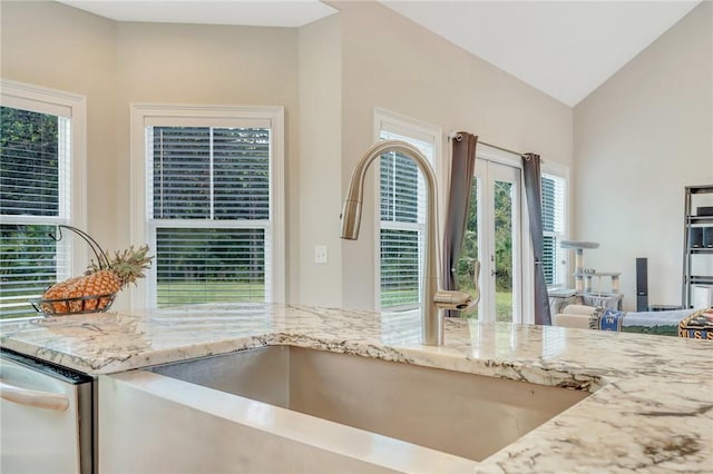 kitchen featuring light stone countertops, sink, dishwasher, and vaulted ceiling