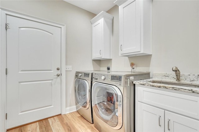 laundry area featuring light hardwood / wood-style flooring, cabinets, sink, and washing machine and clothes dryer