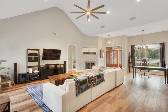 living room featuring high vaulted ceiling, ceiling fan with notable chandelier, and light wood-type flooring