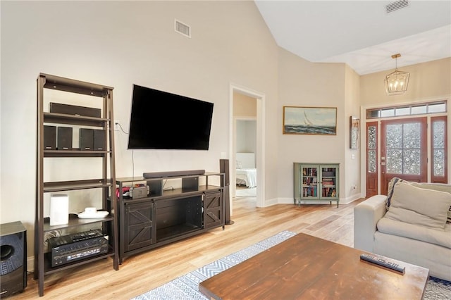 living room featuring an inviting chandelier, high vaulted ceiling, and light hardwood / wood-style flooring