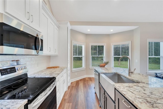 kitchen featuring white cabinetry, light wood-type flooring, light stone counters, and appliances with stainless steel finishes