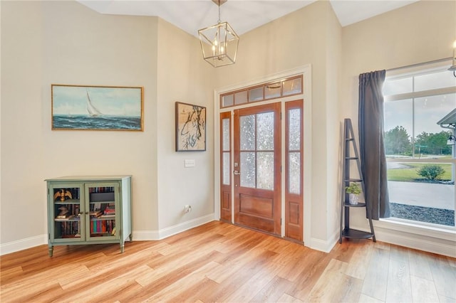 foyer entrance with a healthy amount of sunlight, an inviting chandelier, and light hardwood / wood-style flooring