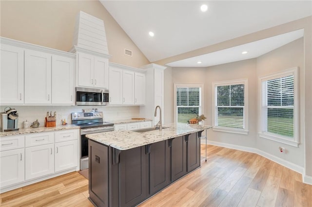 kitchen with stainless steel appliances, sink, a center island with sink, white cabinets, and light hardwood / wood-style floors