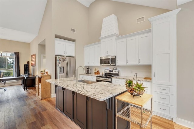 kitchen with sink, light hardwood / wood-style flooring, an island with sink, appliances with stainless steel finishes, and white cabinetry