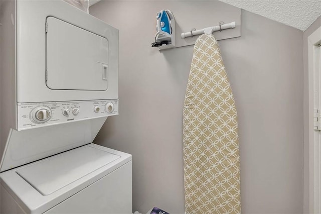 clothes washing area featuring a textured ceiling and stacked washing maching and dryer