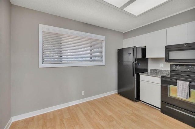 kitchen featuring white cabinetry, black appliances, a textured ceiling, dark stone counters, and light wood-type flooring