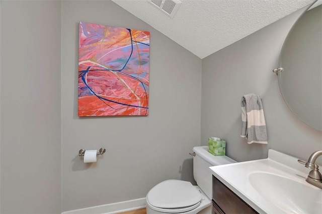 bathroom with vanity, lofted ceiling, a textured ceiling, and toilet